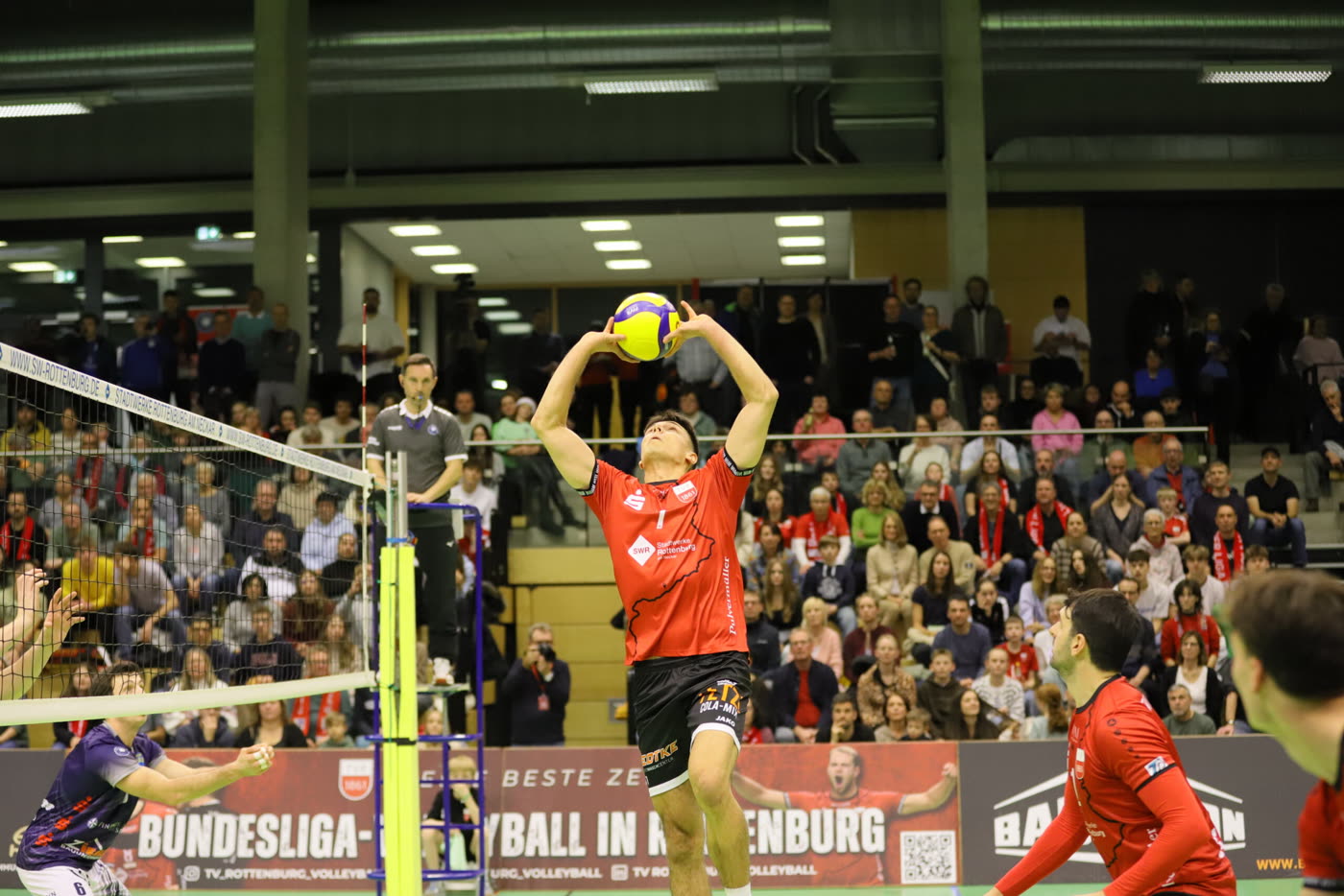 Ein Zuspieler des TV Rottenburg spielt den Ball vor voll besetzter Tribüne.